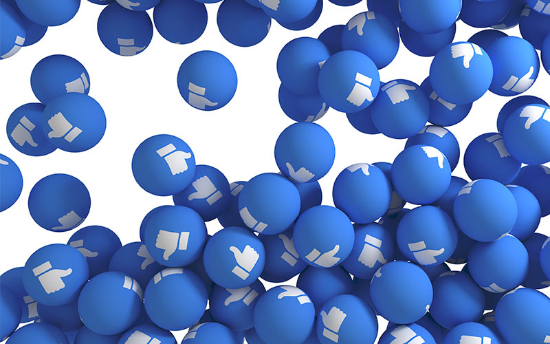 Pequenas bolas, como as de piscina de bolinha, azuis com o like no Facebook desenhado.