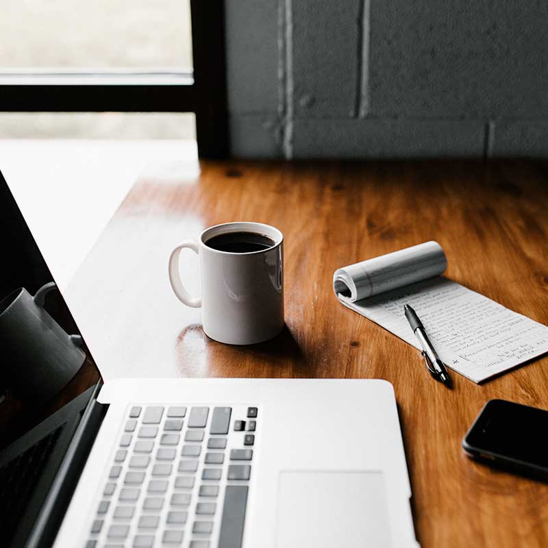 Imagem de uma mesa com laptop e caderneta, ilustrando home office